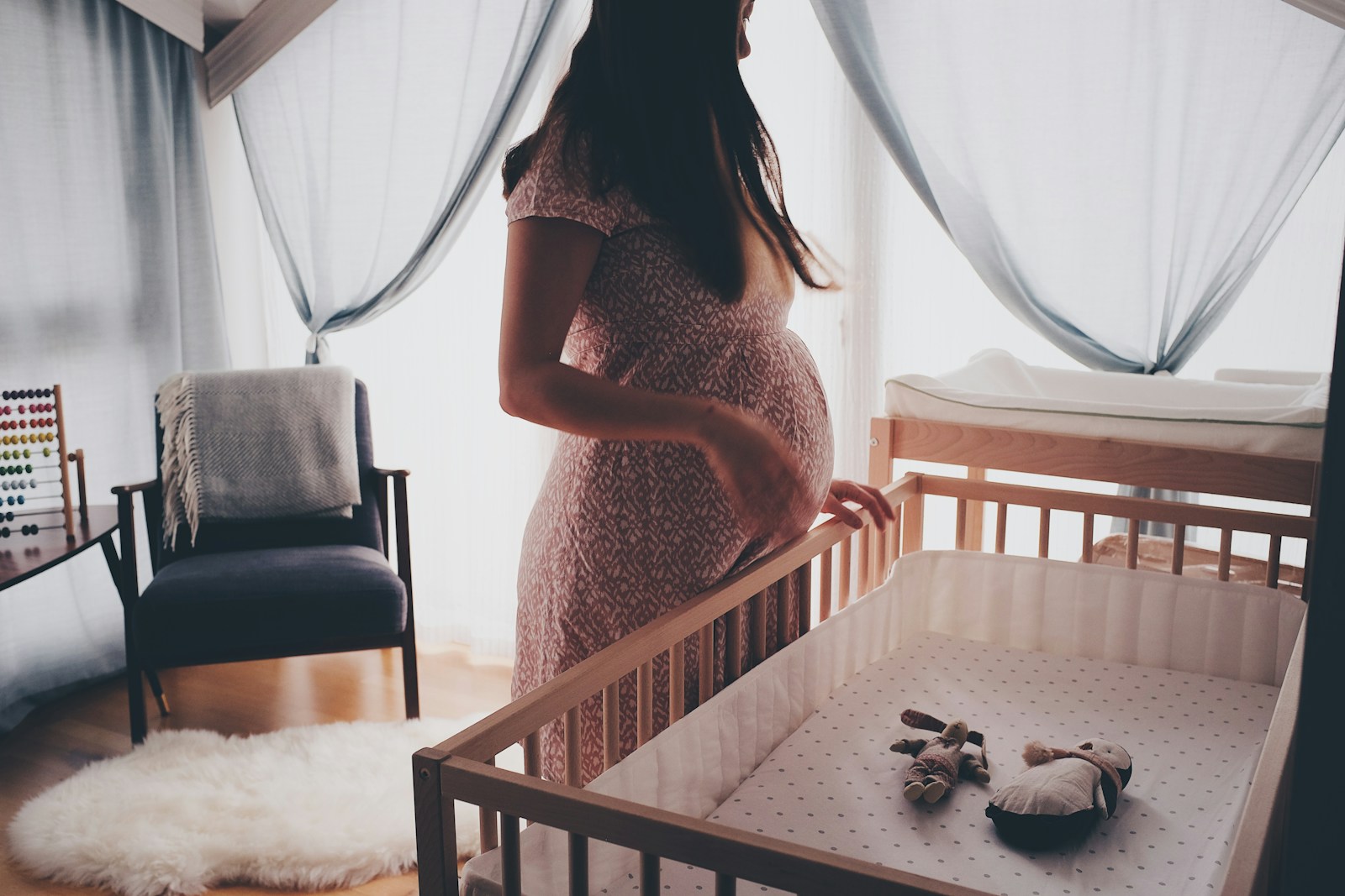 een zwangere vrouw naast een kinderbedje
