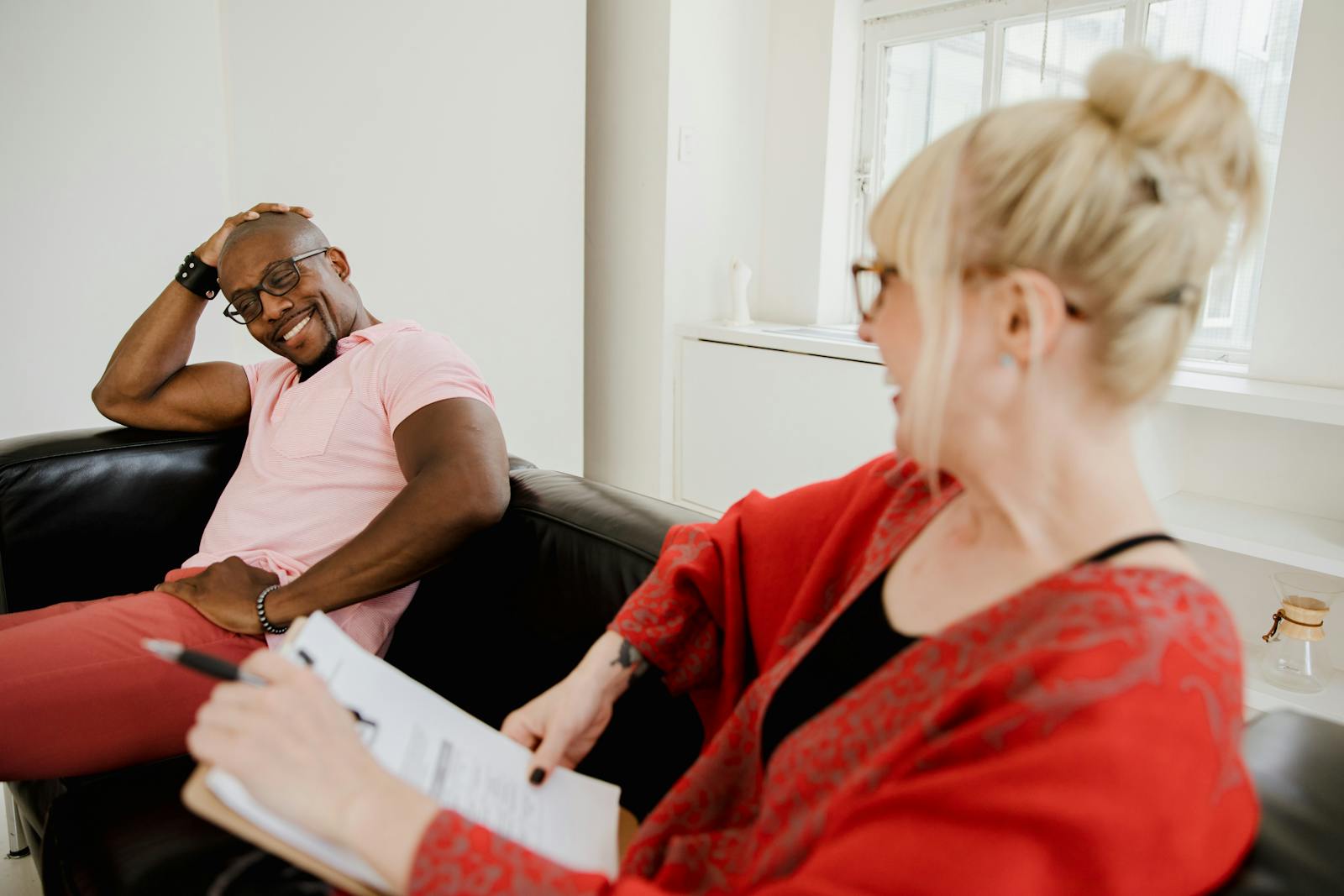 Smiling man talking to female counselor during a therapy session in a bright, modern room.